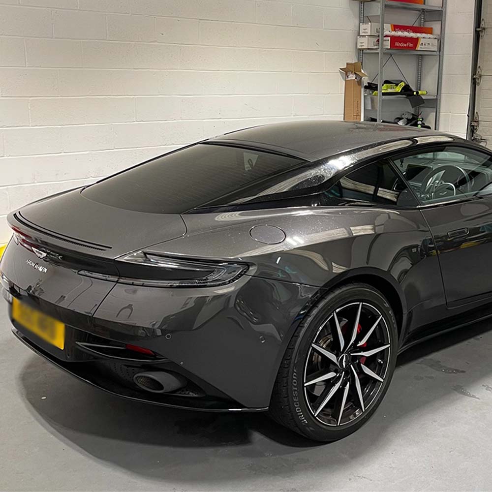 A grey Aston Martin DB11 with limo tinted windows, the darkest style available.